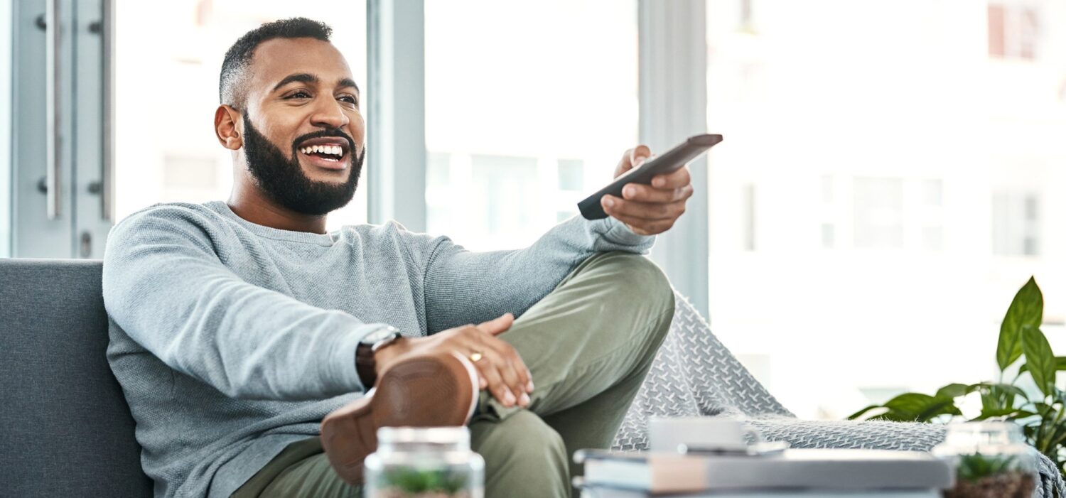 Shot of a handsome young man watching television at home